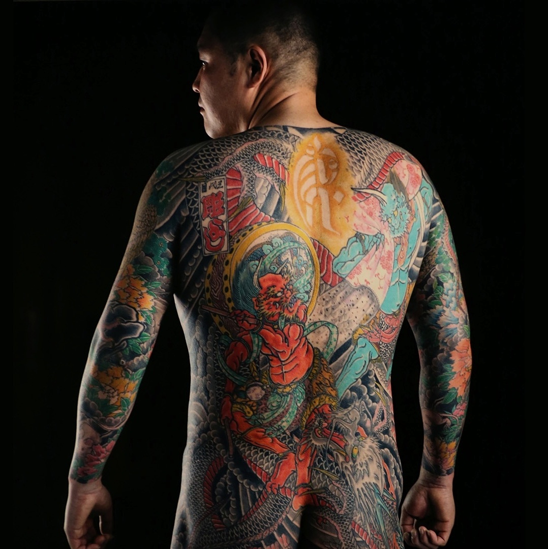 Mestre feminino faz tatuagem nas costas para cliente masculino no