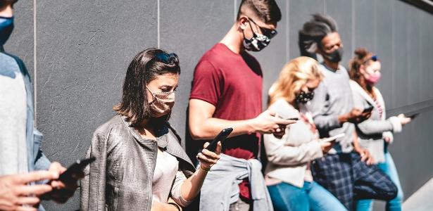 Pessoas de máscara olhando o celular