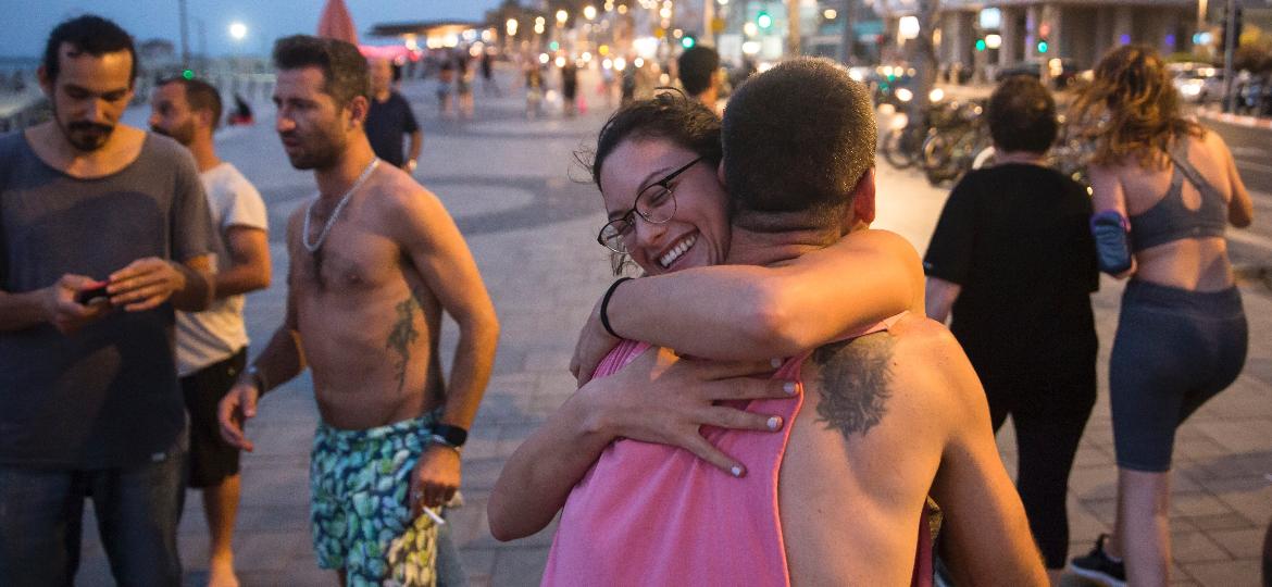 Jovens se abraçam em calçadão da praia em Tel Aviv, Israel, após controle do contágio do coronavírus - Amir Levy/Getty Images