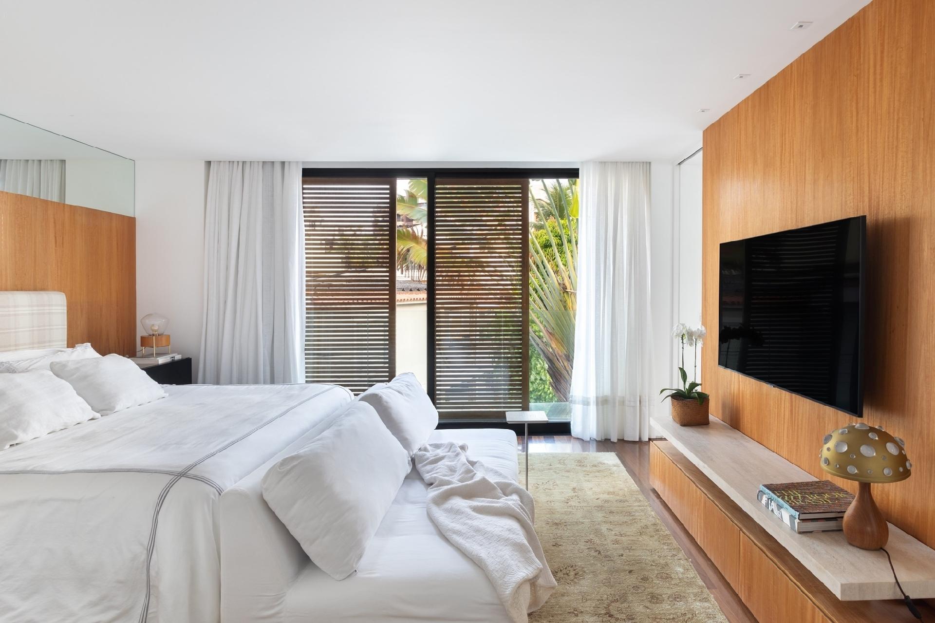 No quarto, o branco predomina, aliado à madeira que traz aconchego ao espaço. - Luiza Schreier/Divulgação