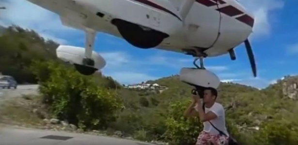 O trem de pouso da aeronave quase atinge a cabeça do fotógrafo - Reprodução/Youtube