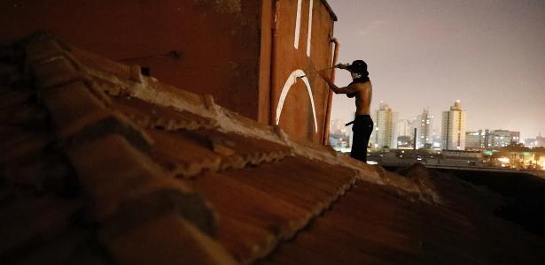 Jovem pinta muro em comunidade de SP - Reuters/Nacho Doce - Reuters/Nacho Doce