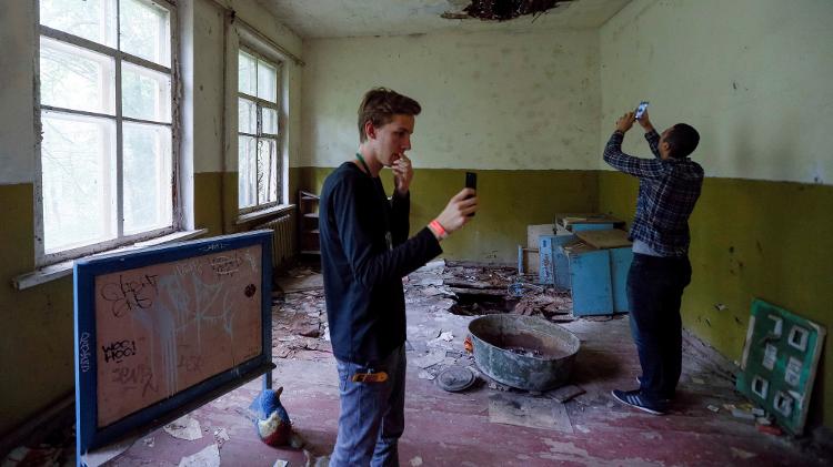 Turistas fotografam uma escola abandonada na vila de Kopachi - Valentyn Ogirenko/Reuters - Valentyn Ogirenko/Reuters