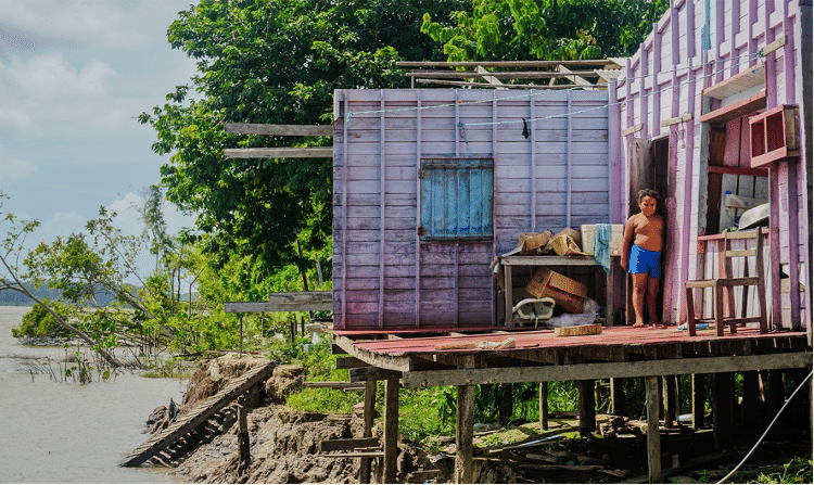 Uma família ainda ocupando uma casa prestes a cair no Rio Amazonas devido à erosão ao redor da comunidade Macedônia
