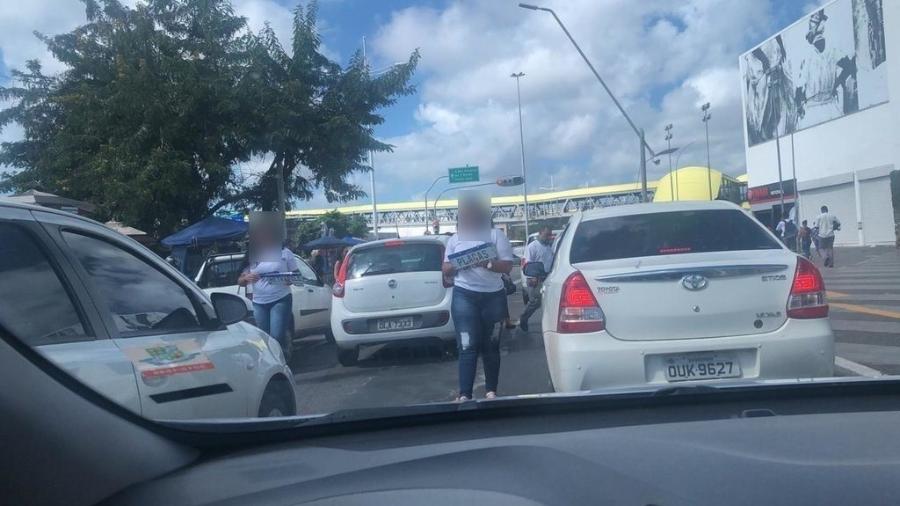 Funcionárias de empresa fornecedora de placas vendem produto em meio ao trânsito em Salvador (BA); prática é irregular - Reprodução