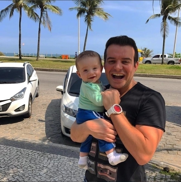 24.out.2016 - O sertanejo Belutti posa sorridente com o filho, Luís Miguel, na Barra da Tijuca, no Rio. "#LM veio conhecer o Rio de Janeiro com papai e mamãe. Acho que está gostando, olha a cara dele...", disse o cantor - Reprodução/Instagram/belutti