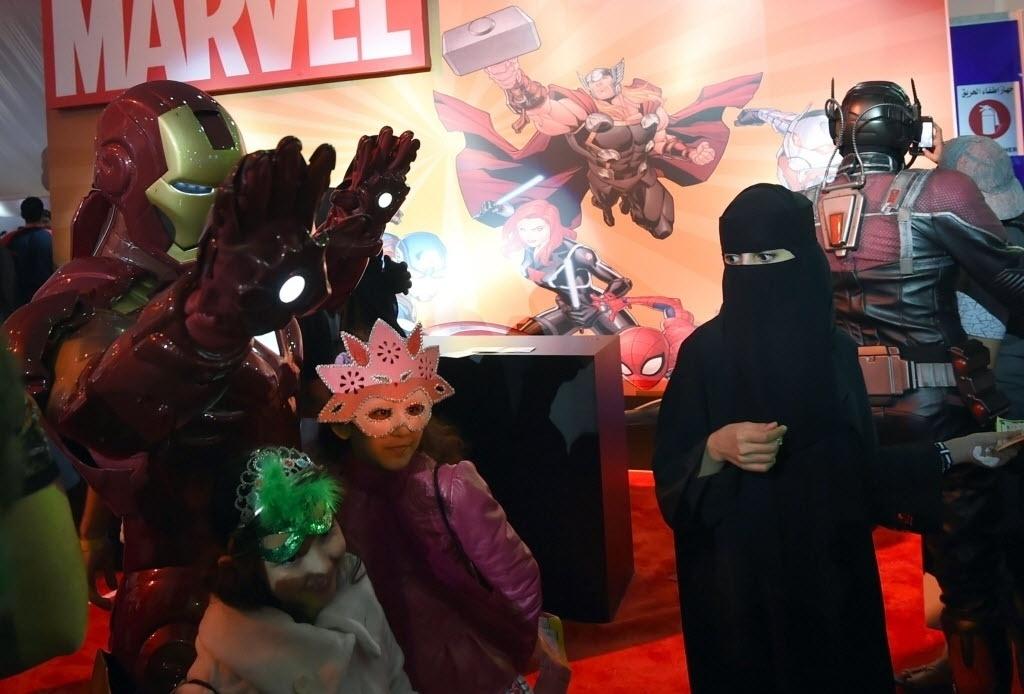 Fayez Nureldine/AFP Photo - Mulher saudita observa crianças tirando posando para foto com cosplay do Homem de Ferro