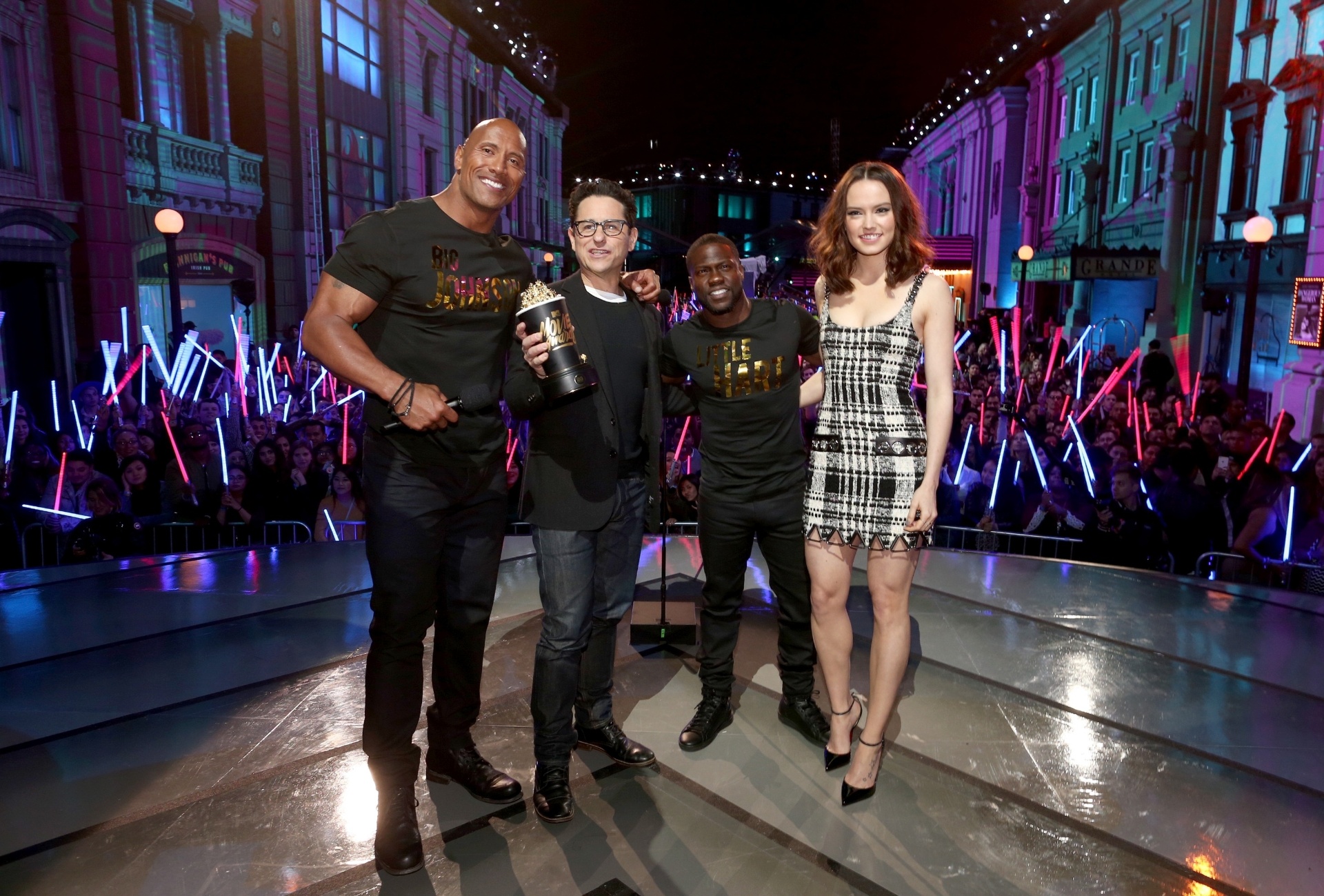 10.abr.2016 - O diretor J.J. Abrams e a atriz Daisy Ridley com os apresentadores The Rock e Kevin Hart: "Star Wars: O Despertar da Força" foi o vencedor das categorias melhor filme, melhor vilão e revelação (Ridley) - Getty Images