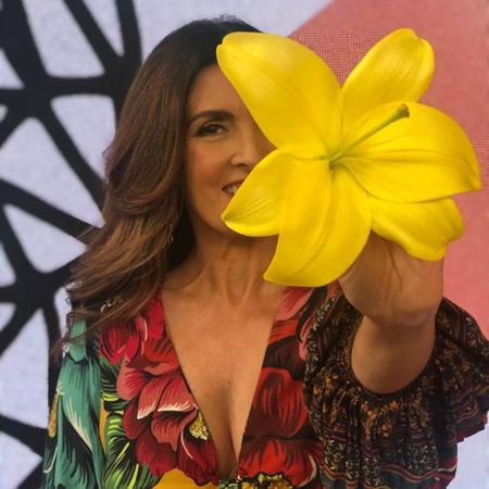 Fátima aparece com um look florido e aponta para a câmera com uma flor amarela em mãos - Reprodução/Instagram