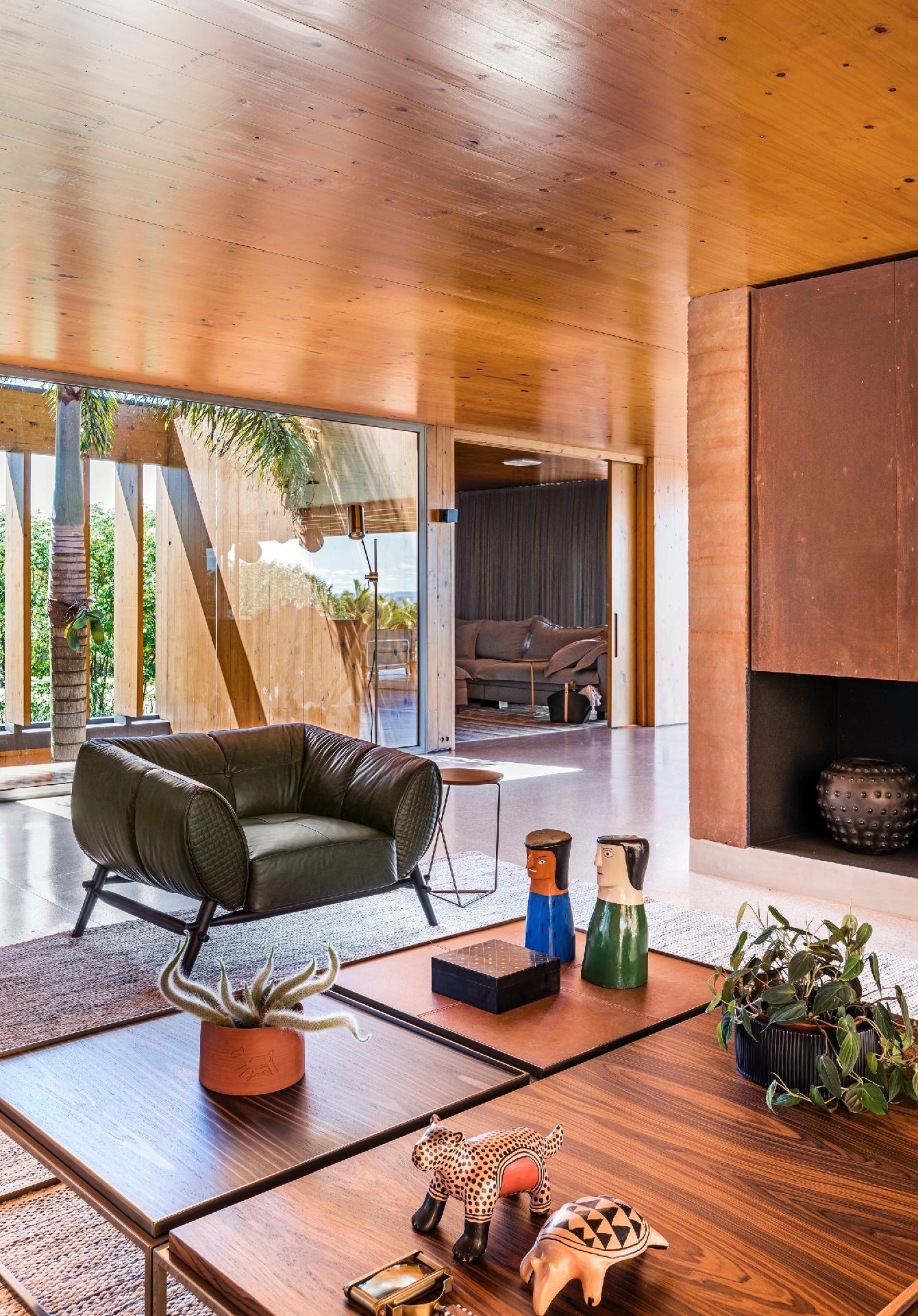 Na sala de estar com lareira, o artesanato brasileiro sobre as mesas de centro falam mais sobre as escolhas que refletem a família. Luz natural e ventilação cruzada são garantidos por vãos amplos e aberturas para ver a paisagem. - Renato Navarro/Divulgação