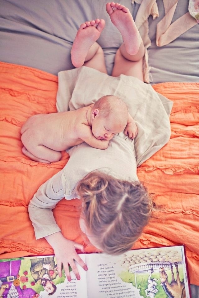 Enquanto a irmã mais velha lê, o bebê dorme tranquilamente sobre ela. Um momento especial de interação entre as crianças que pode dar mais charme ao álbum do segundo filho - Reprodução/Pinterest