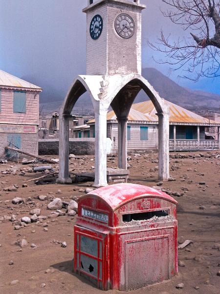 A torre do relógio e uma cabine telefônica sob as cinzas das erupções de 1995 em Plymouth, Montserrat - Education Images/Education Images/Universal Image