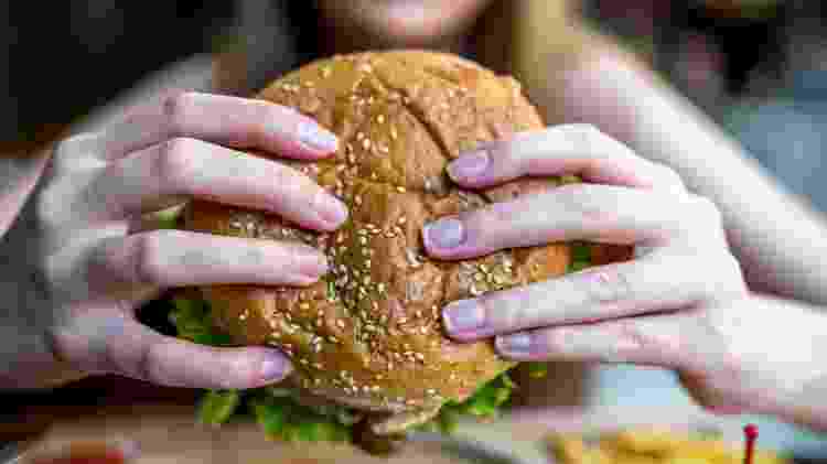 fast food, pessoa comendo hamburguer - iStock - iStock