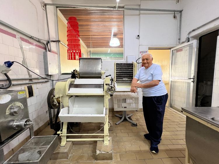Martino ao lado da máquina de massas considerada a primeira do Brasil e mais antiga em funcionamento