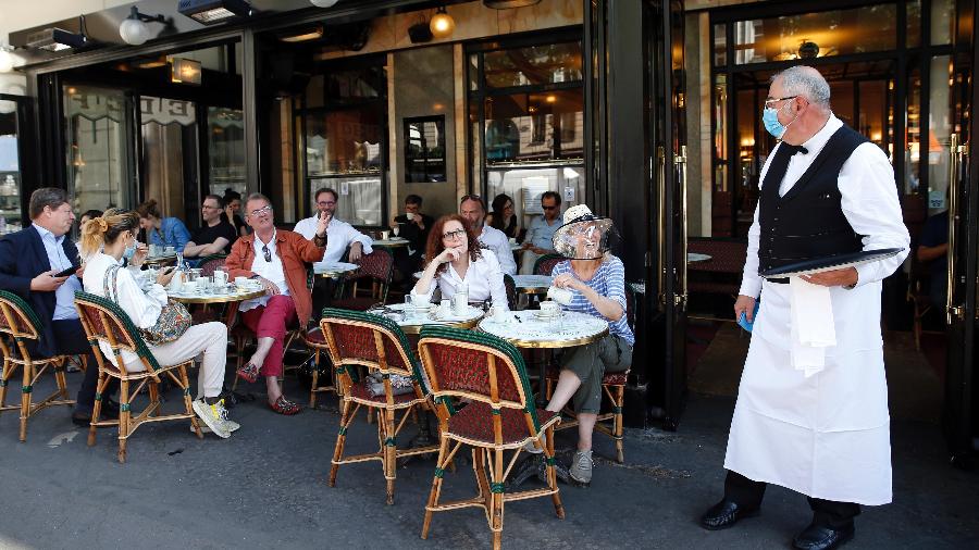 Garçom usa máscara para servir os clientes em café de Paris, que reabre após o confinamento  - Getty Images