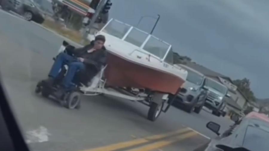 Homem reboca lancha com cadeira de rodas elétrica - Reprodução