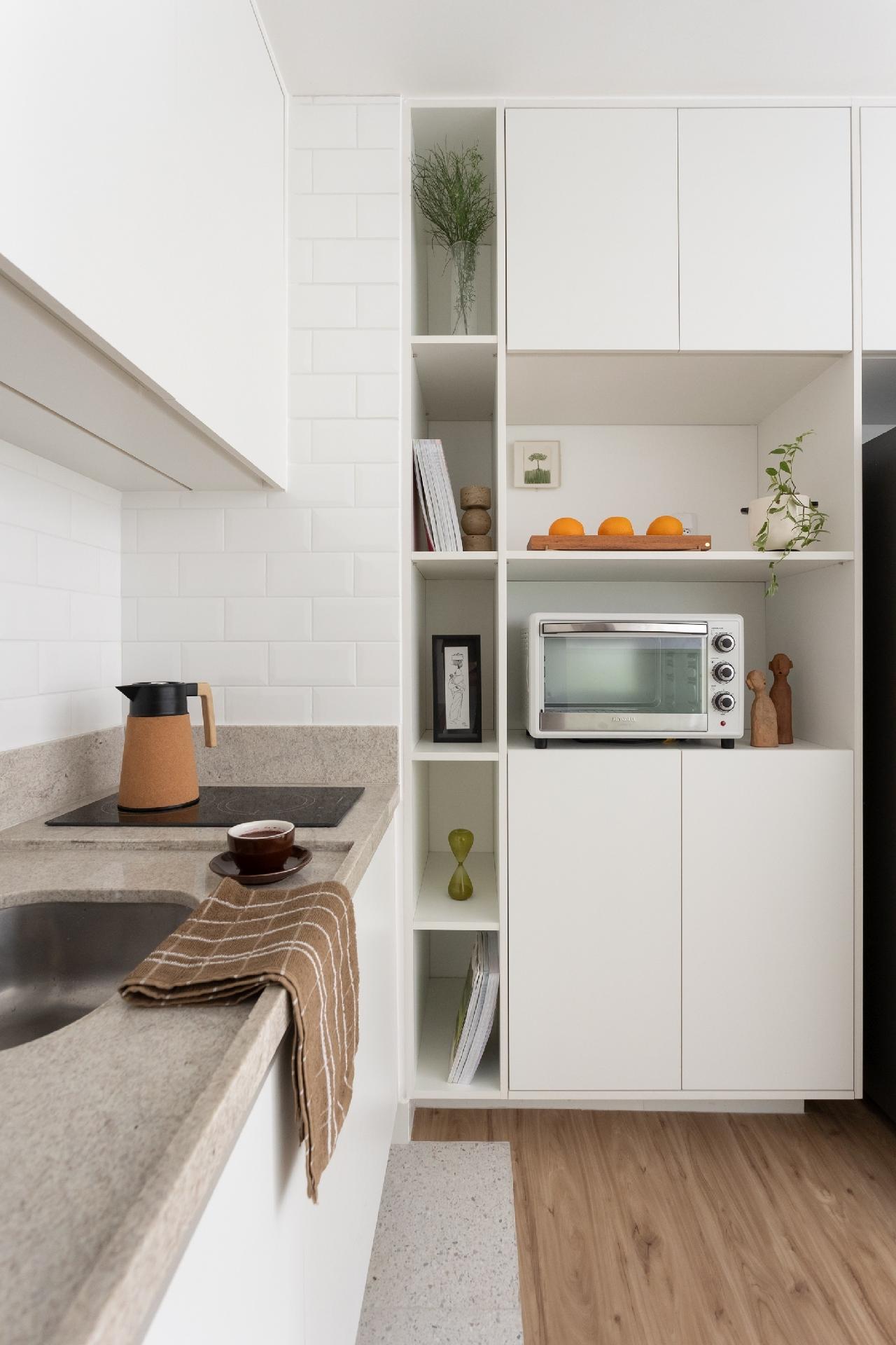 No armário da lateral, além de espaço para forno e micro-ondas, nichos dão leveza visual, o que é importante em um apartamento integrado. - Thiago e Dam Mol/Divulgação