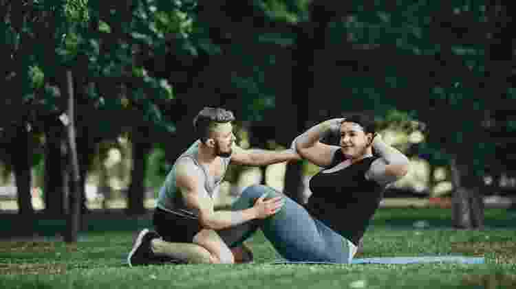 profissional de educação física, treinador orientando aluno, personal, exercício para emagrecer - iStock - iStock