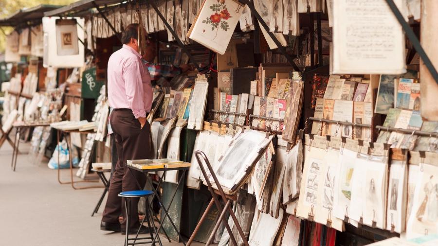 Um buquinista (ou 'bouquiniste', em francês) de Paris, lugar vende livros e revistas antigas nas margens do rio Sena