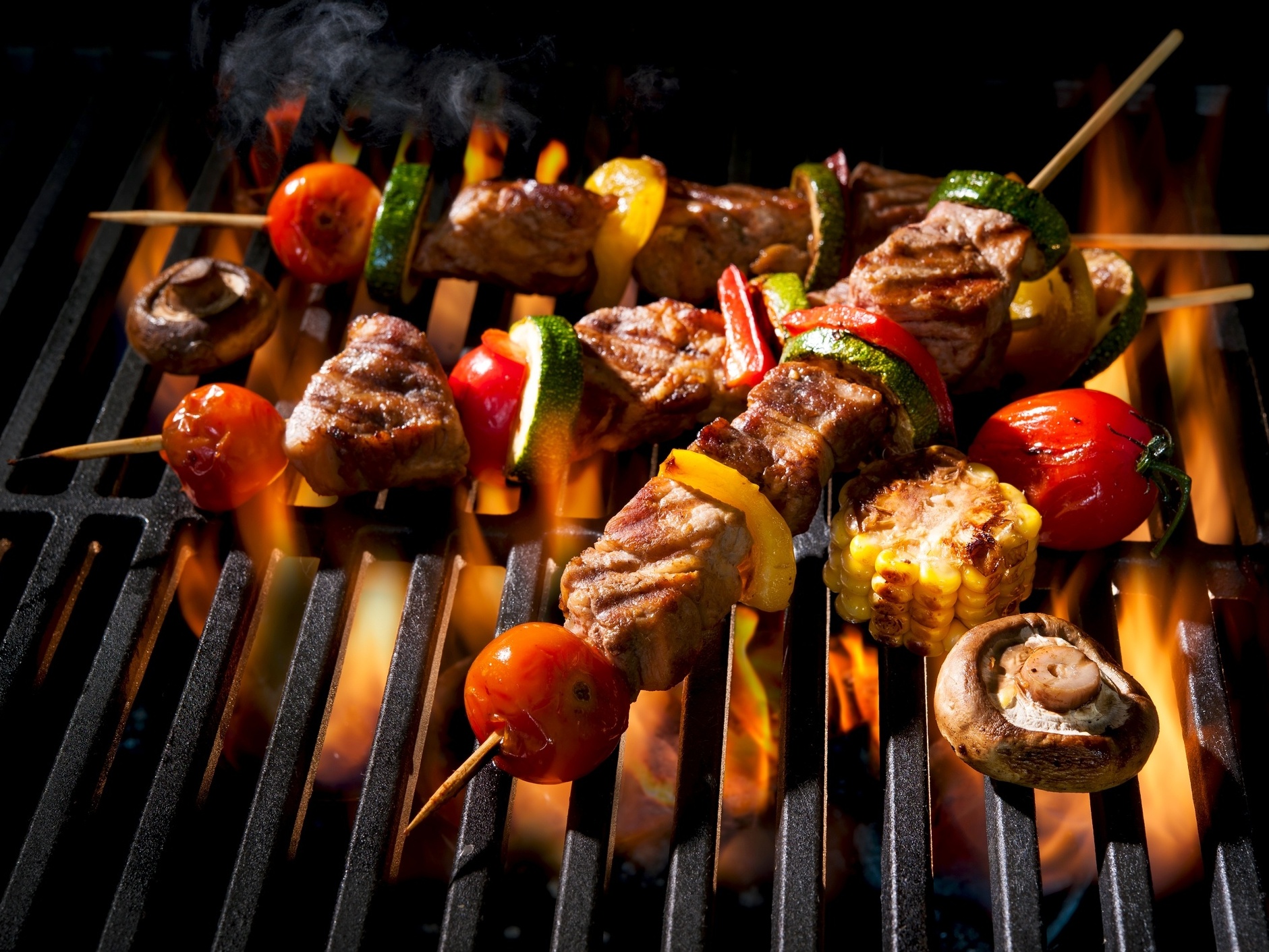 A imagem mostra uma churrasqueira acesa e lotada de espetos de carne para  um suculento churrasco.Tanto o Brasil quanto o…