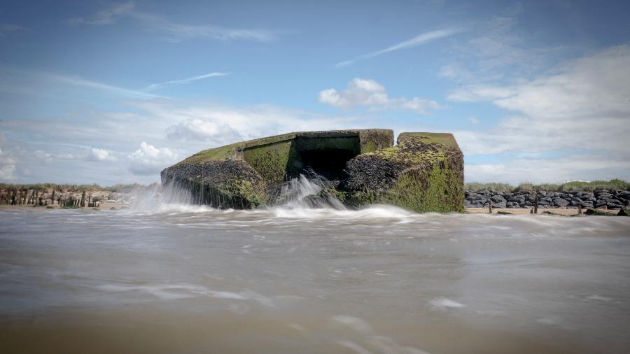 Foto de bunker parcialmente submerso na praia de codinome Juno, na Normandia