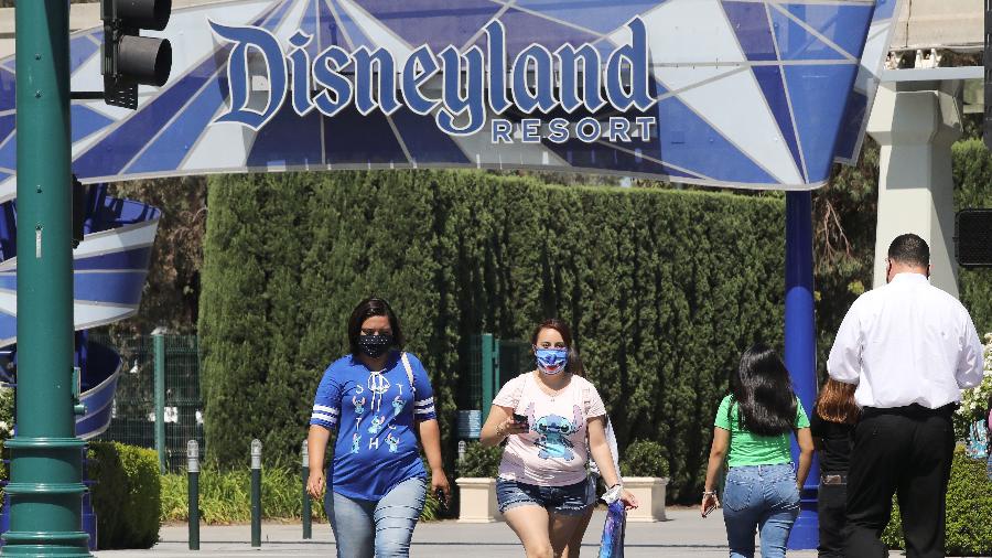 Visitantes com máscaras circulam perto da Disneylândia, na Califórnia - Getty Images