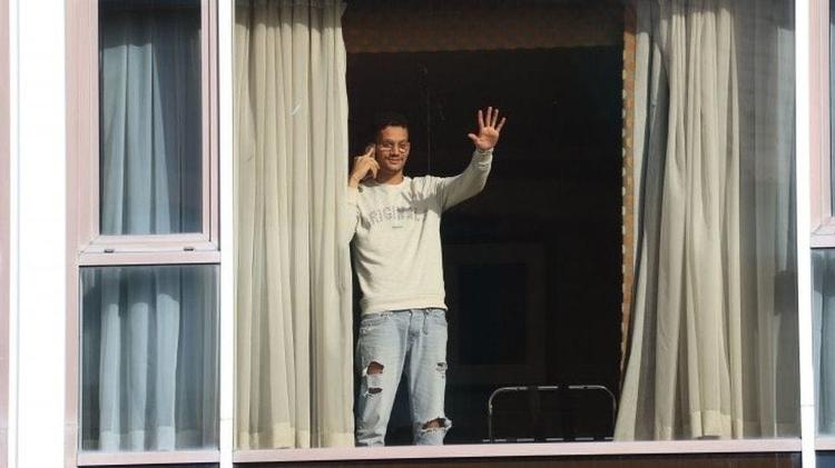 Roger Gonçalves, que é do Brasil e viajou por Madri para chegar ao Reino Unido, acena da janela do Hotel Radisson - PA MEDIA - PA MEDIA