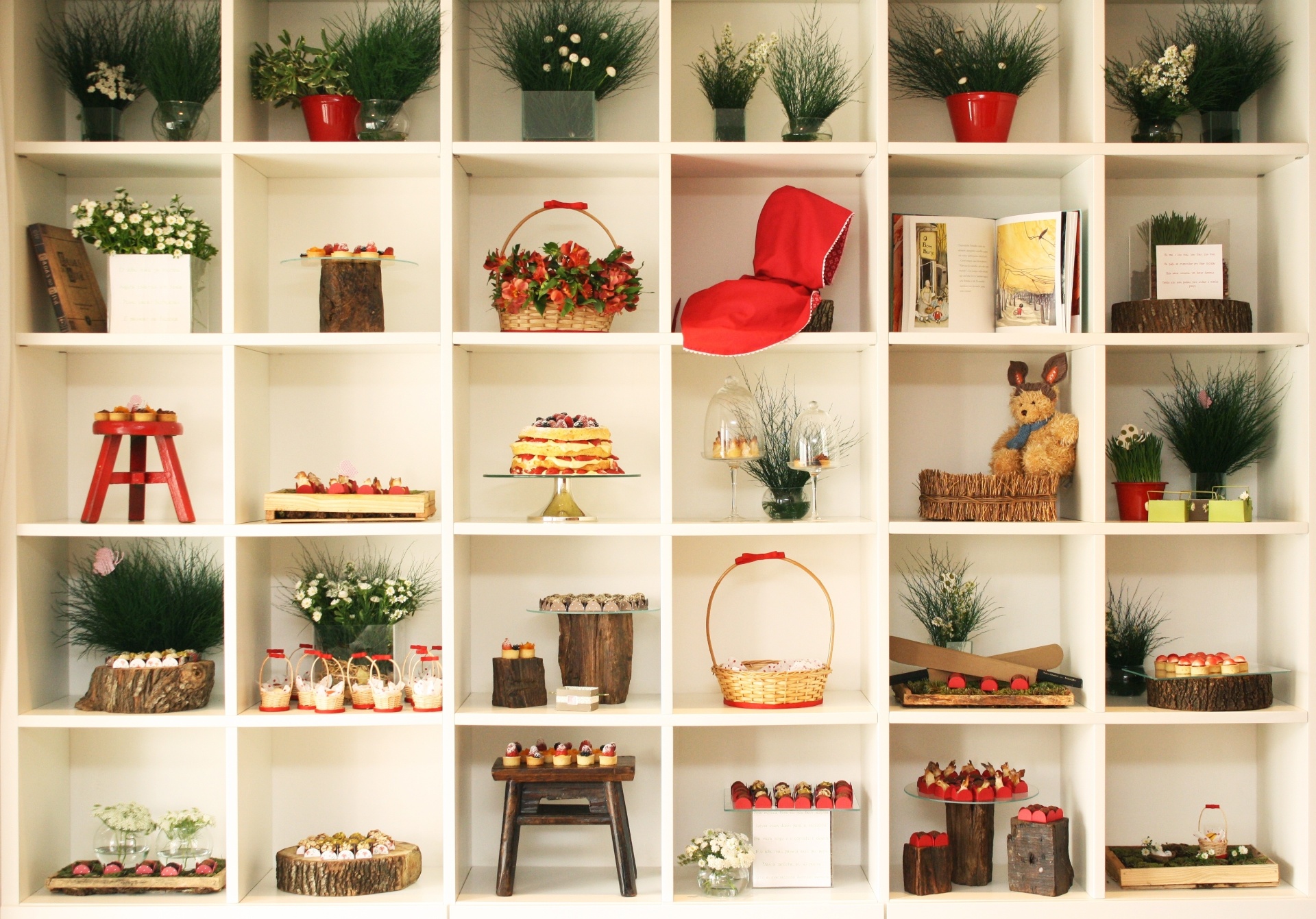 A tradicional mesa do bolo deu espaço a uma estante de madeira na parede. Os docinhos foram espalhados em meio a vasinhos de plantas e flores, além de objetos de madeira para compor o tema "Chapeuzinho Vermelho" - Rachel Clarck/Divulgação