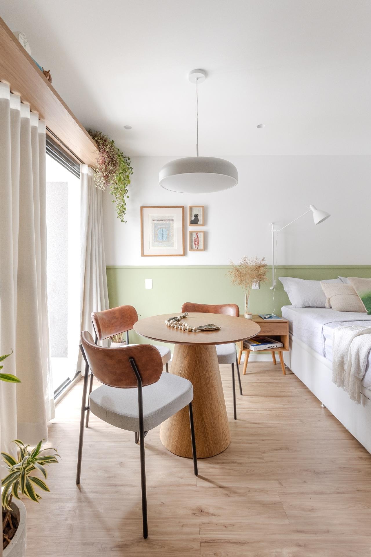 Diante da pequena varanda, uma mesa de jantar redonda setoriza a sala de jantar. Repare acima da cortina: uma prateleira acomoda plantas e traz charme ao apartamento. - Thiago e Dam Mol/Divulgação