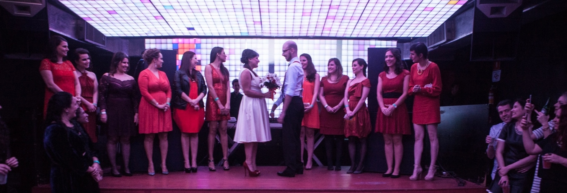 As madrinhas dos noivos escolheram vestidos curtos e em tons de vermelho, para testemunhar a cerimônia - Divulgação/Anna Silveira