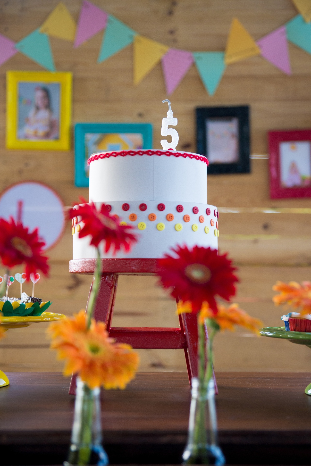 O bolo cenográfico, confeccionado pela Festas Ecológicas, uniu o conceito da reciclagem à paleta de cores do tema da festa. Feito de uma caixa de madeira, o bolo foi encapado de papel e foram colados botões e sianhinhas para remeter à roupa da boneca Emília - Karl Ellwein/Dueto em Versos/Divulgação
