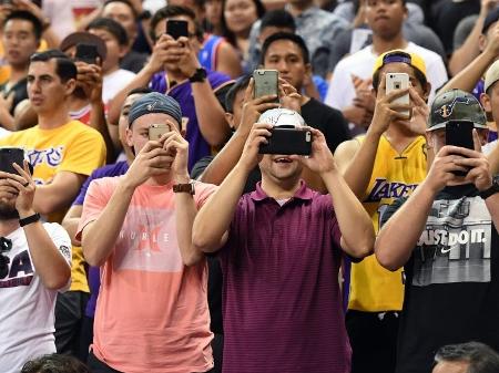 Jovens usam celular em jogo de basquete nos Estados Unidos - Ethan Miller/Getty Images/AFP