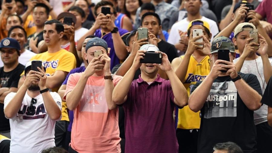 Jovens usam celular em jogo de basquete nos Estados Unidos - Ethan Miller/Getty Images/AFP