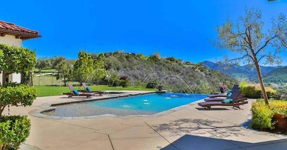 A piscina da mansão de Britney Spears é decorada com cinco espreguiçadeira em redor de sua borda. Mini jatos de água caem no tanque, que tem vista para as montanhas. A residência está à venda por R$ 32 milhões, na Califórnia, Estados Unidos
