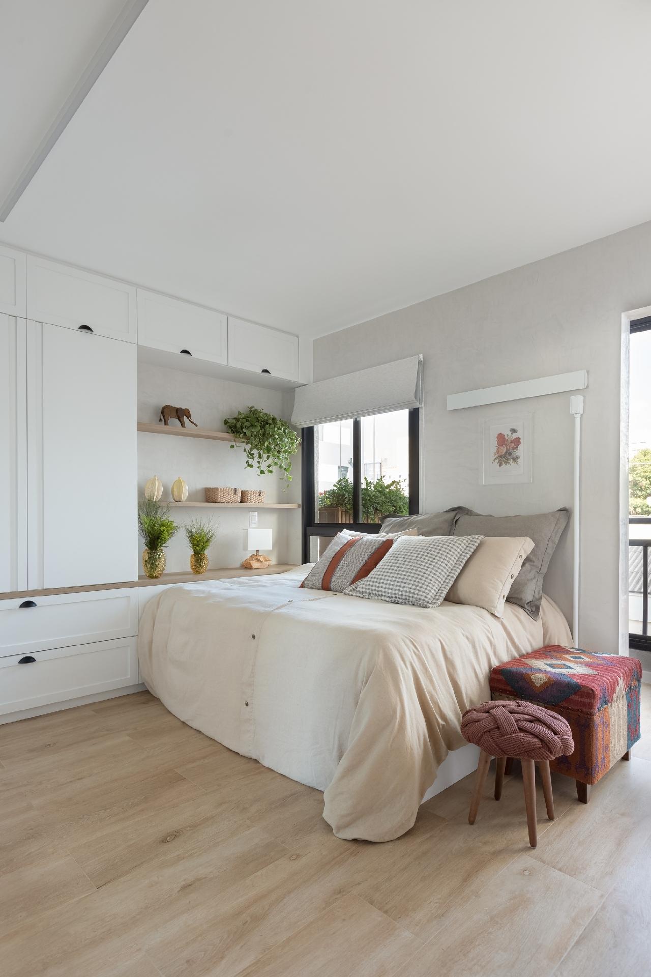 Na área do quarto, aberta para a sala, a cama em tamanho generoso tem bicama e foi encostada na parede. Como os moradores não cozinham em casa, a opção de integrar tudo foi possível. - Monica Assan/Divulgação