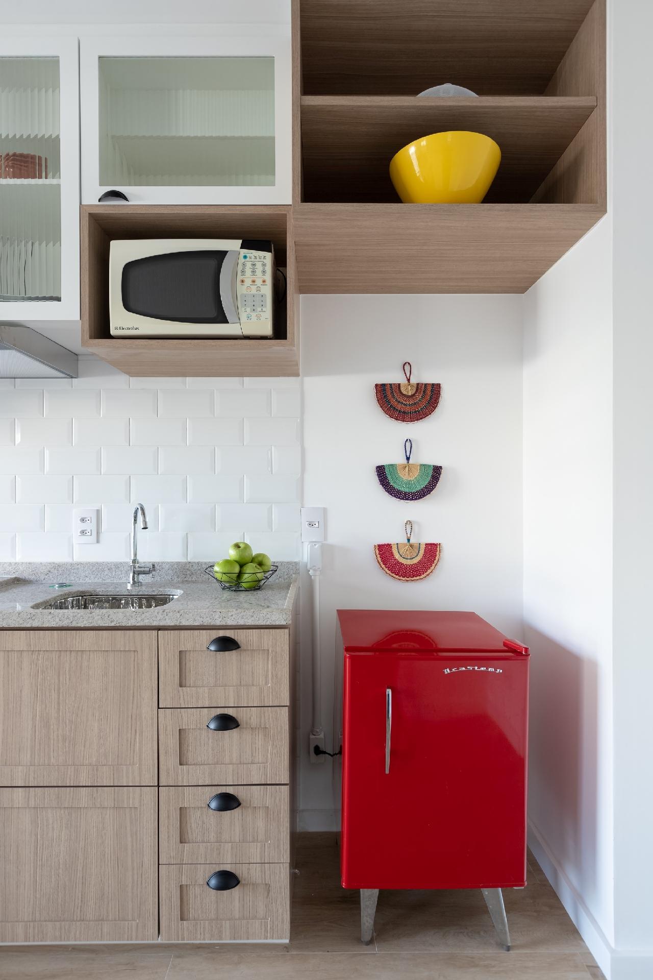 Materiais neutros na base do apartamento dão uniformidade e unidade ao apê. Pontos de cor, como a pequena geladeira e os leques trazidos de viagem pela moradora, além dos tecidos terrosos e étnicos, surgem para dar alegria e personalidade. - Monica Assan/Divulgação