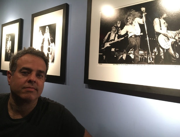 Marc Canter posa em frente a galeria de fotos feitas por ele em diversos shows dos anos 1980. Em primeiro plano, os Guns n" Roses em show de 1985. Ao fundo, Madonna e Eric Clapton - James Cimino/UOL