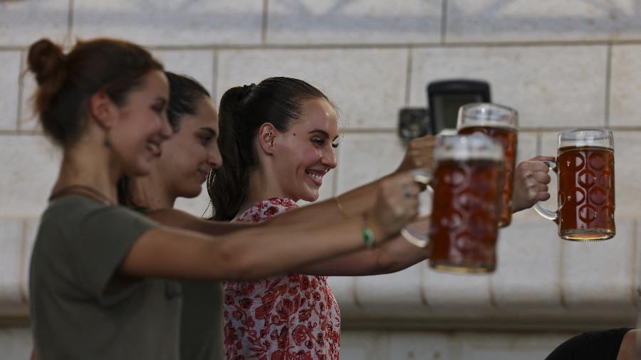 Visitantes mostram suas canecas em evento realizado em Taybeh  - ABBAS MOMANI/AFP