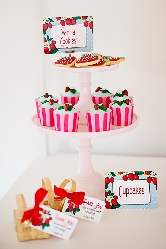 Ajudando a compor a decoração da mesa principal deste aniversário com tema quitanda do morango, cestinhas de palha com docinhos que serviram como lembrancinhas. No prato de dois andares, cupackes de morango e biscoitos decorados no formato da fruta - Reprodução/Pinterest