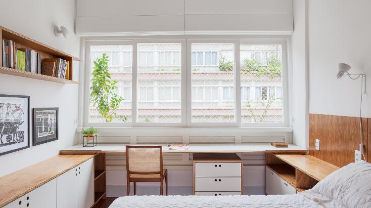 O formato retangular alongado do quarto, que garante boa circulação ao redor da cama, permitiu a criação de um espaço agradável, sem pesar o clima de trabalho na área de descanso. O desafio da arquiteta Mariana Wilderom (https://www.instagram.com/mariana.wilderom/), em parceria com o escritório Sabará Arquitetura (https://www.instagram.com/sabaraarquitetura/), foi evitar o aspecto corporativo, o que levou a móveis que conversam entre si em todo o cômodo. A escolha da bancada não foi à toa: posicionada abaixo da ampla janela, absorve a excelente luminosidade.  - Alessandro Guimarães - Alessandro Guimarães