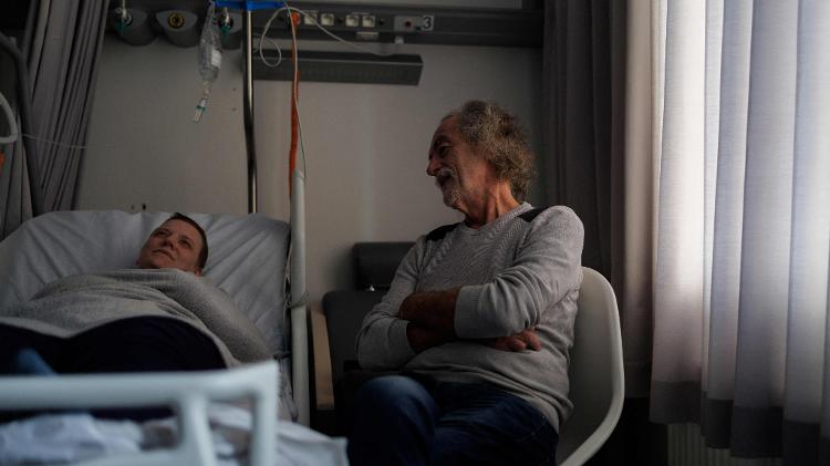 O cuidador e ex-médico Denis Rousseaux conversa com Lydie Imhoff em um quarto de hospital na Bélgica, em 1º de fevereiro de 2024, enquanto Imhoff espera a chegada do médico no dia de sua eutanásia.