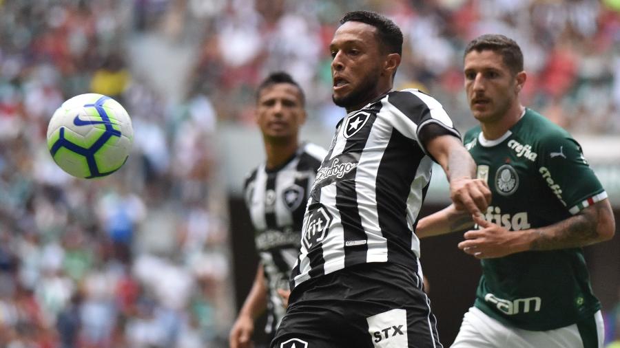 Jogador do Botafogo disputa lance com jogador do Palmeiras durante partida no estadio Mané Garrincha - Andre Borges/AGIF