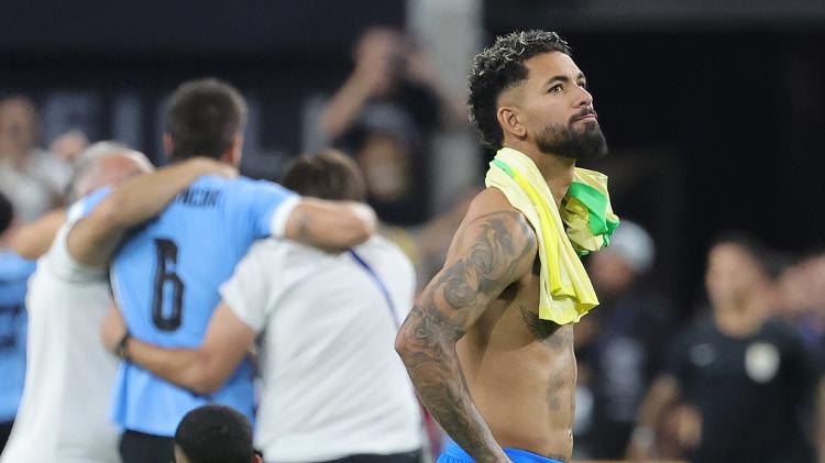 Douglas Luiz, do Brasil, se lamenta enquanto uruguaios comemoram classificação na Copa América