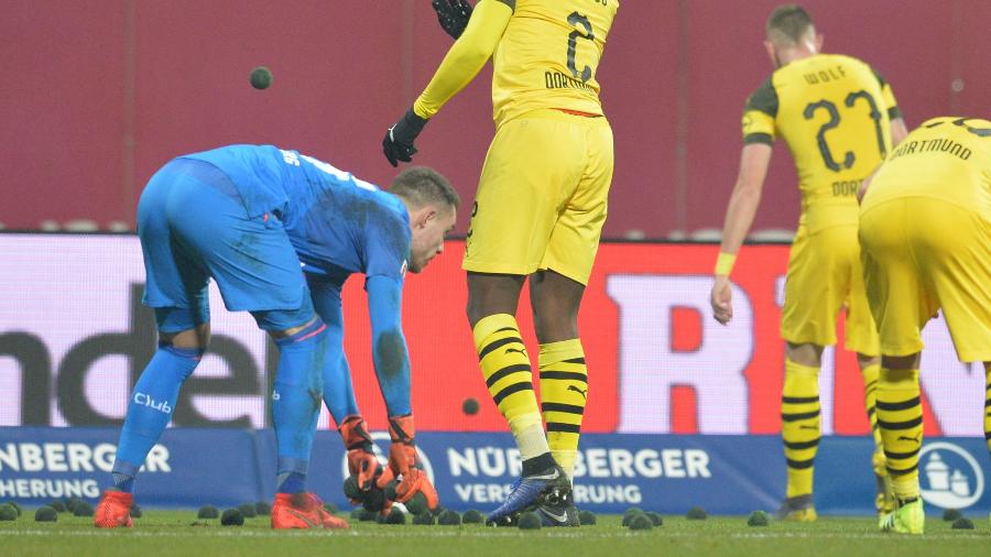 Jogadores recolhem bolinhas pretas arremessadas em jogo entre Borussia Dortmund e Nuremberg - TIMM SCHAMBERGER/AFP