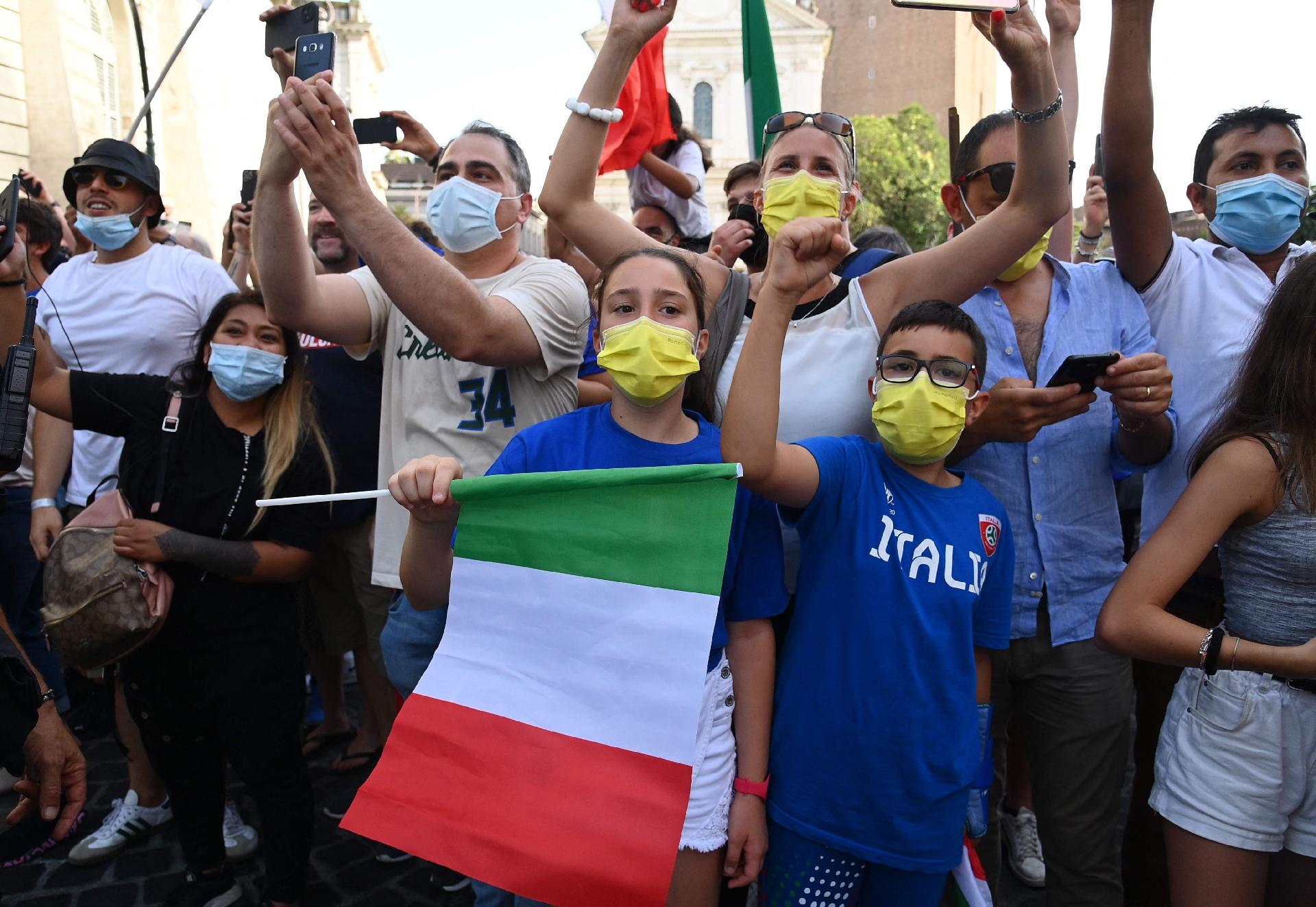 Fans stand by as a bus transporting Italy's national football team drives through Rome after leaving the Quirinale presidential palace in Rome on July 12, 2021, following a ceremony a day after Italy won the UEFA EURO 2020 final football match between Italy and England. (Photo by Vincenzo PINTO / AFP) - VINCENZO PINTO/AFP