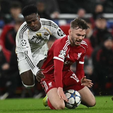 Vini Jr, do Real Madrid, derruba Bradley, do Liverpool, durante jogo da Champions