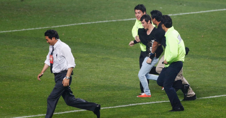 11.jun.2013 - Seguranças retiram torcedor que invadiu o gramado durante a vitória da Coreia do Sul sobre o Uzbequistão