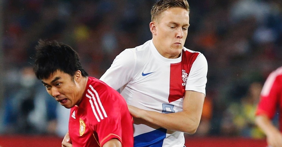 11.jun.2013 - Zhao Xuri, da China, disputa jogada com o holandês Jens Toornstra durante amistoso em Pequim