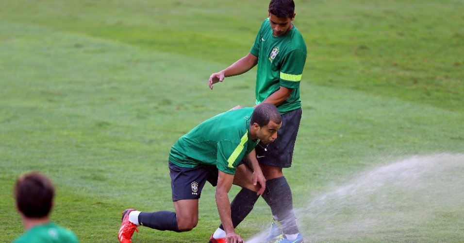 14.jun.2013 - Meia Lucas tenta desligar sistema de irrigação durante treino da seleção brasileira