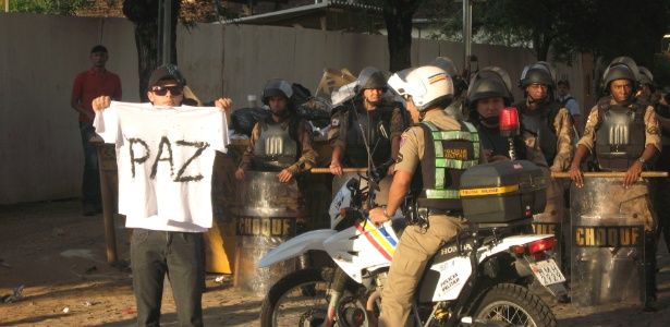 Manifestante exibe pedido de paz em camisa perto de policiais da Tropa de Choque em BH